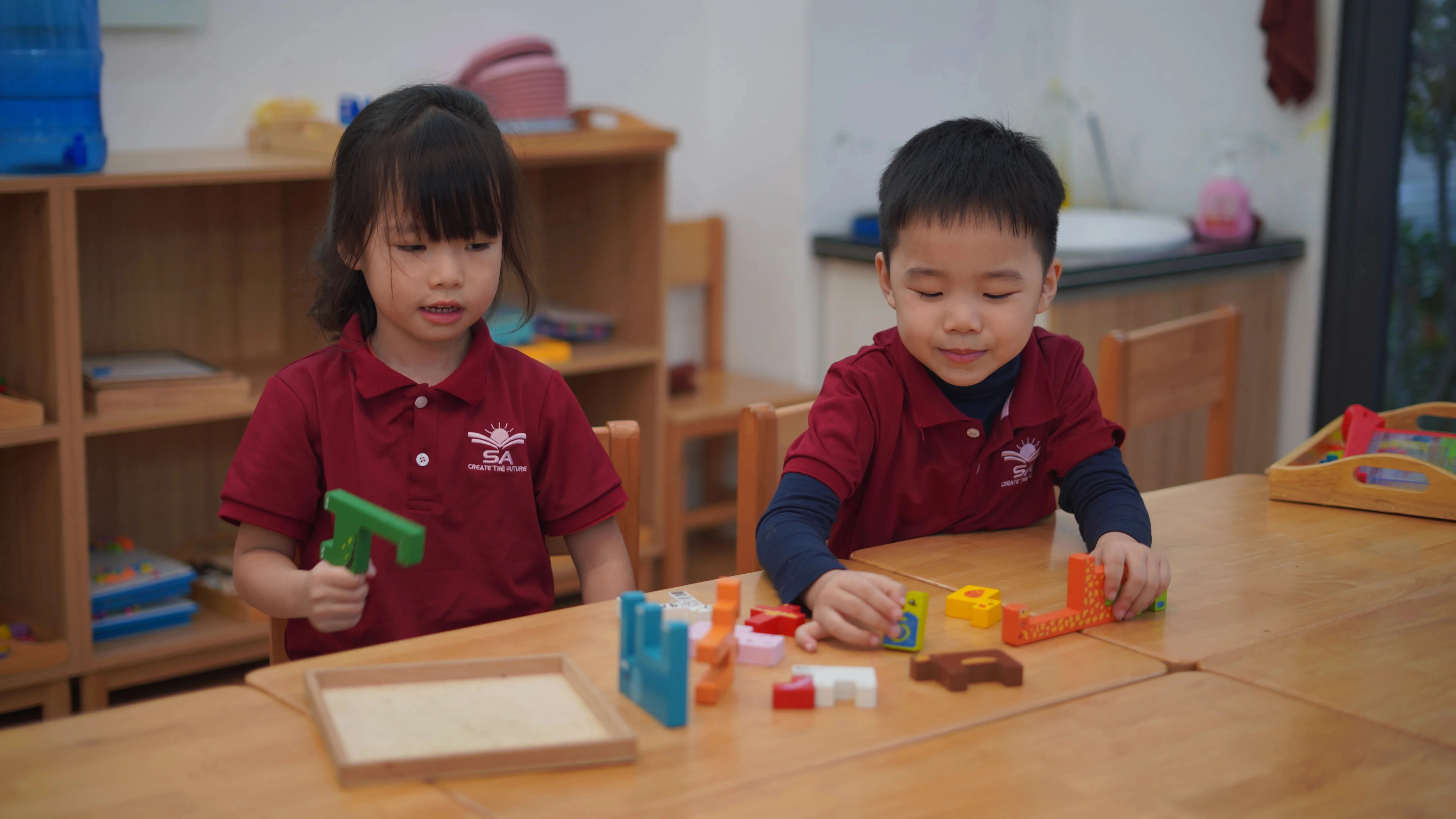 Hai bé ECE làm việc nhóm với khối gỗ